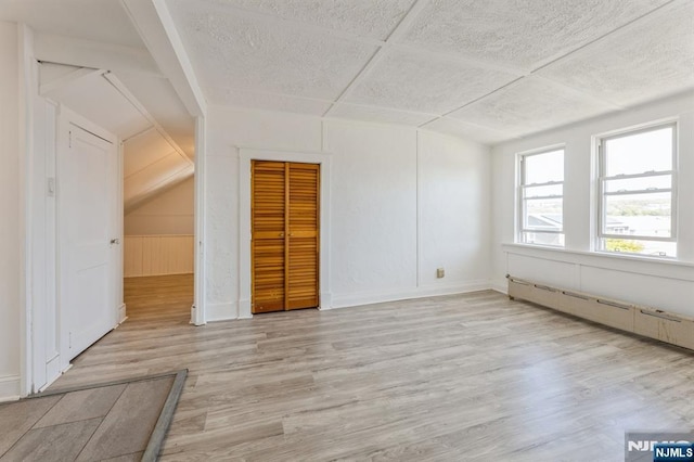 bonus room with light wood-style flooring and a baseboard heating unit