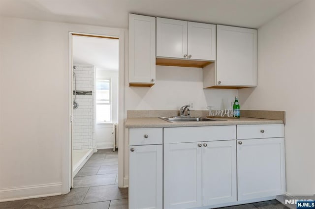 kitchen featuring a sink, light countertops, white cabinetry, baseboards, and light tile patterned floors