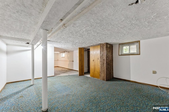 below grade area featuring carpet floors, baseboards, and a textured ceiling