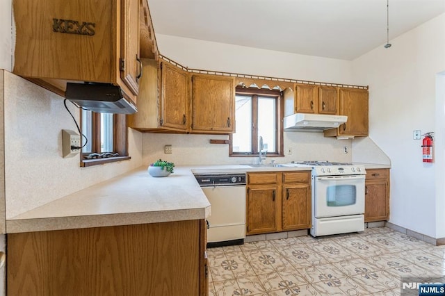 kitchen featuring brown cabinetry, a sink, under cabinet range hood, and white appliances