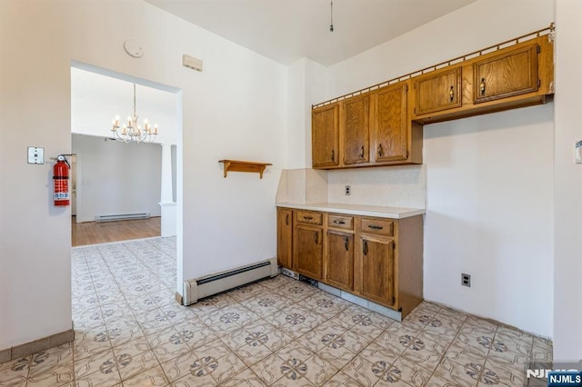 kitchen with brown cabinetry, backsplash, baseboard heating, light countertops, and a notable chandelier