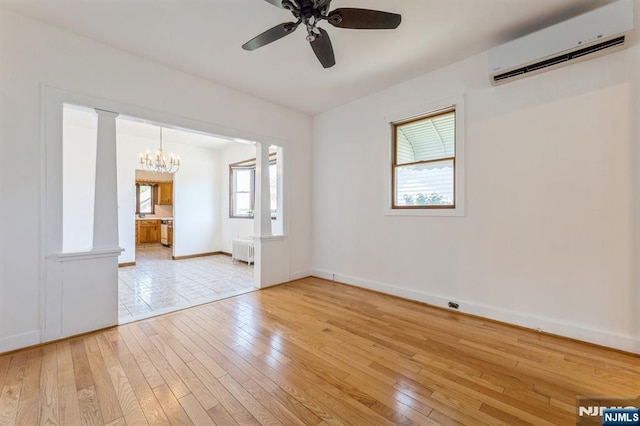 empty room with radiator, baseboards, a wall unit AC, light wood finished floors, and ceiling fan with notable chandelier