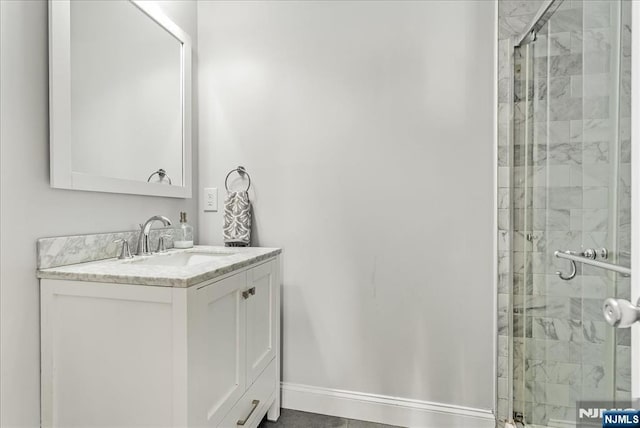 full bathroom with baseboards, a shower stall, and vanity