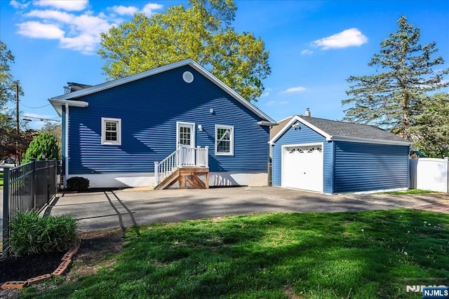 view of front facade with a garage, fence, an outbuilding, and a front lawn