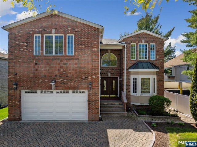 traditional-style house with fence, brick siding, a garage, decorative driveway, and french doors