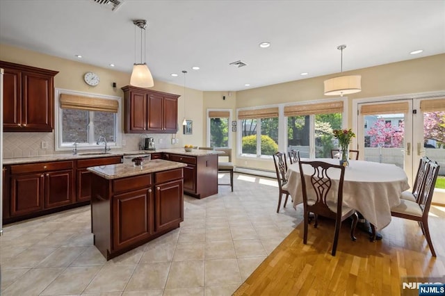 kitchen with visible vents, stainless steel dishwasher, a peninsula, a kitchen island, and backsplash