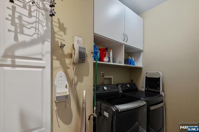 clothes washing area featuring washing machine and clothes dryer and cabinet space