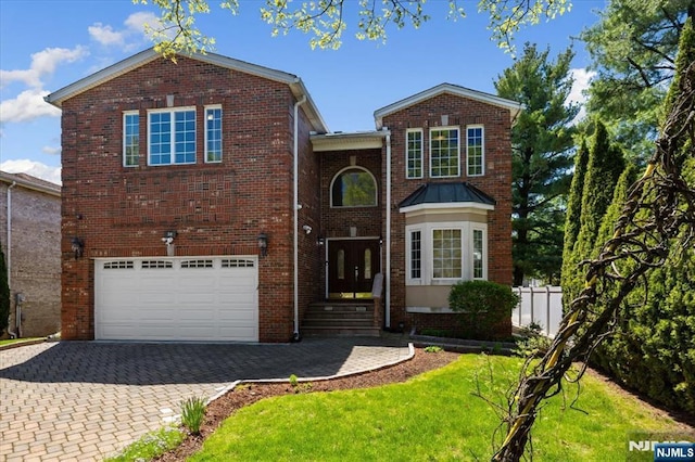 traditional-style home featuring fence, an attached garage, brick siding, a front yard, and decorative driveway