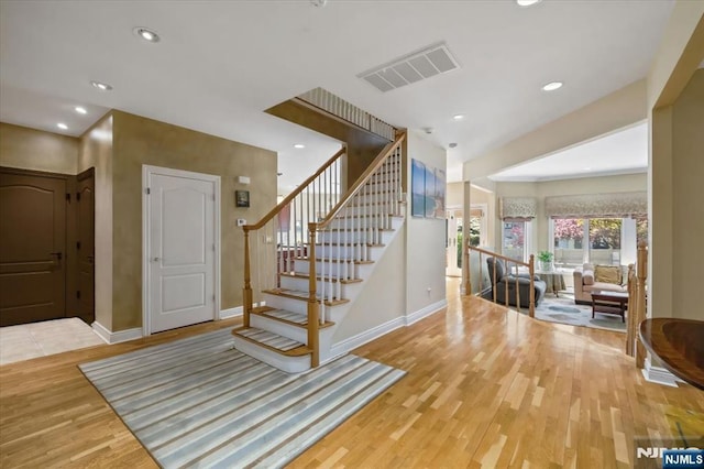staircase featuring baseboards, recessed lighting, wood finished floors, and visible vents
