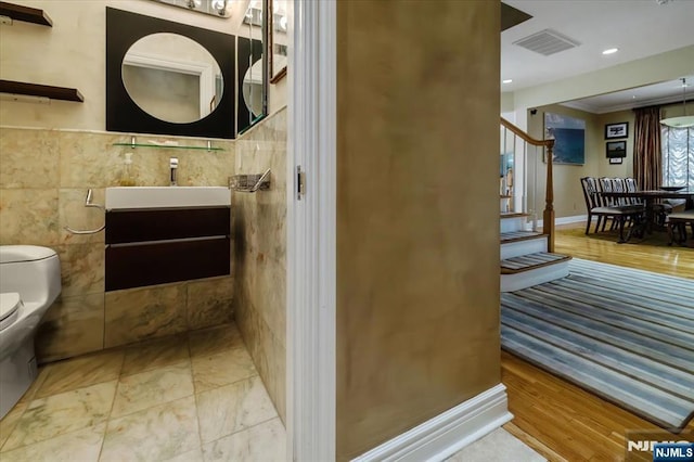 bathroom with visible vents, crown molding, tile walls, vanity, and toilet