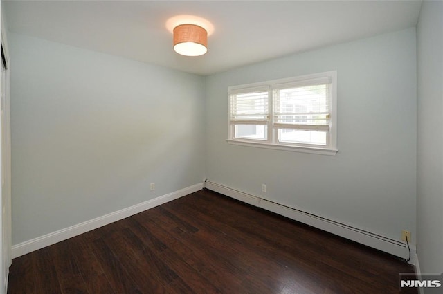 spare room featuring baseboards, a baseboard radiator, and dark wood finished floors