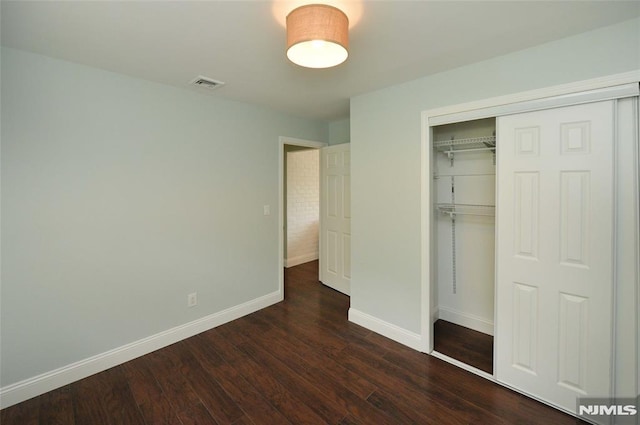 unfurnished bedroom with visible vents, baseboards, dark wood-style flooring, and a closet
