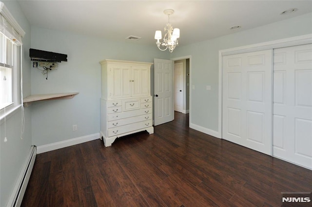 unfurnished bedroom with a notable chandelier, baseboards, a baseboard heating unit, dark wood-style floors, and a closet