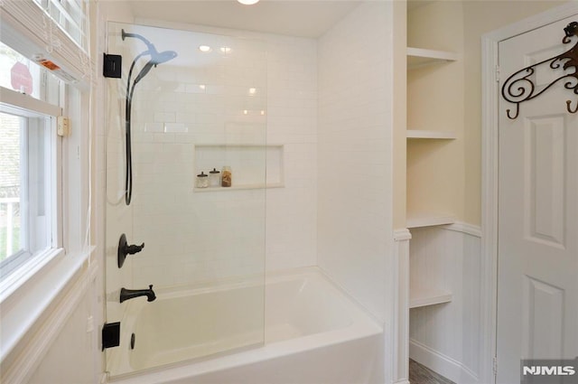 full bathroom featuring shower / bath combination, a wealth of natural light, and a wainscoted wall