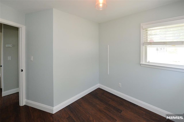 spare room with baseboards and dark wood finished floors