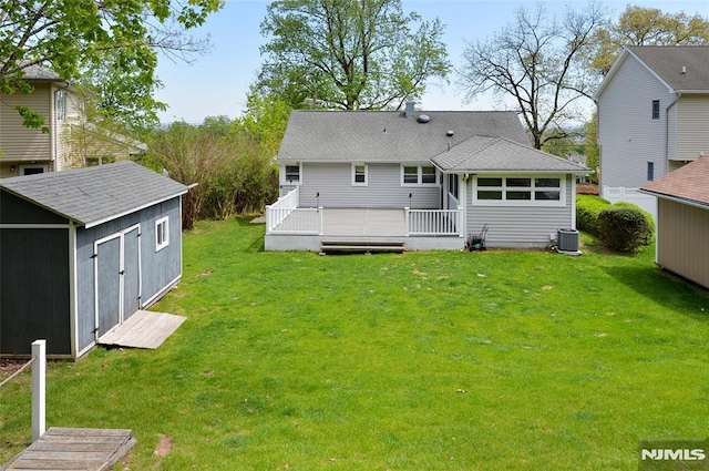 rear view of house featuring a lawn, central AC unit, an outdoor structure, and a shed