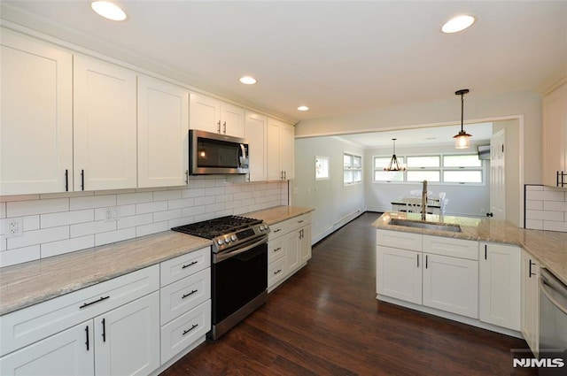 kitchen featuring a sink, a chandelier, stainless steel appliances, a peninsula, and dark wood-style floors