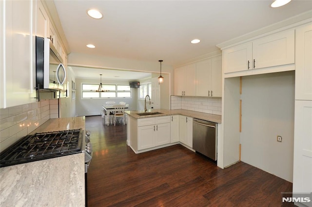kitchen with a sink, dark wood finished floors, appliances with stainless steel finishes, and a peninsula