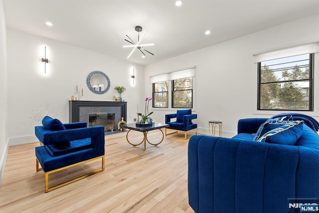 living room featuring light wood-type flooring, a chandelier, a healthy amount of sunlight, and a fireplace