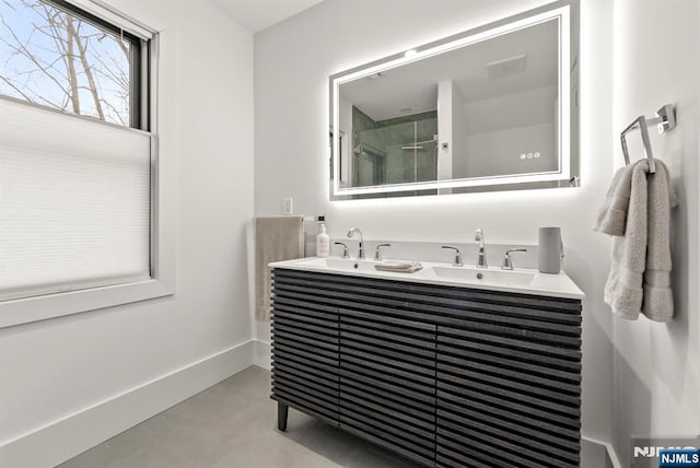 bathroom with double vanity, a sink, baseboards, and an enclosed shower