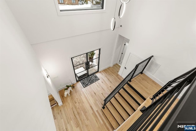 entryway with light wood-style floors, baseboards, and a towering ceiling