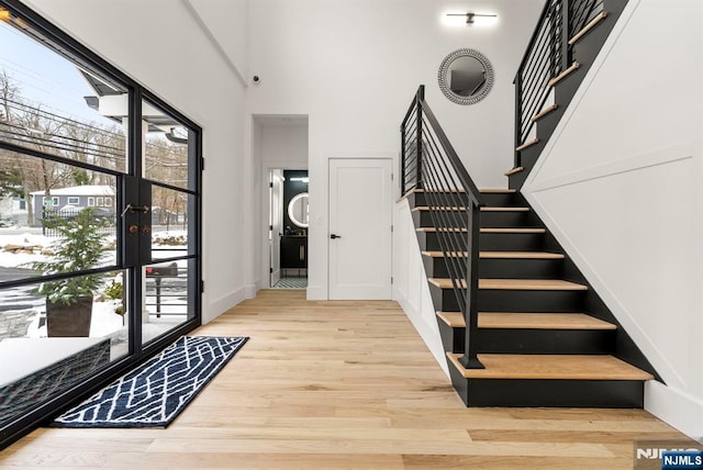 foyer entrance featuring french doors, stairs, wood finished floors, and a towering ceiling