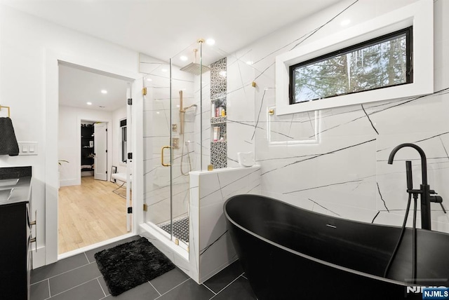 bathroom with recessed lighting, a freestanding tub, a marble finish shower, and tile patterned flooring
