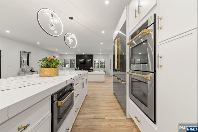 kitchen with light stone counters, open floor plan, stainless steel appliances, recessed lighting, and white cabinetry