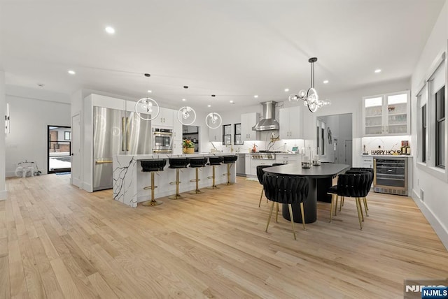 dining room with wine cooler, baseboards, recessed lighting, light wood-type flooring, and a chandelier