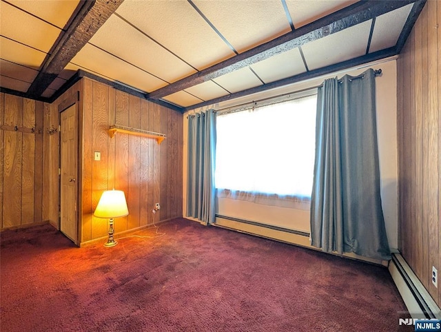 unfurnished room featuring wooden walls, baseboard heating, and carpet