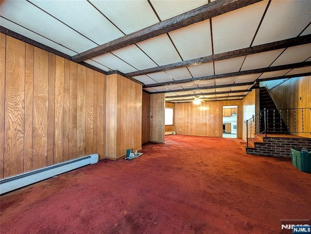below grade area featuring carpet flooring, a baseboard heating unit, wood walls, and stairway
