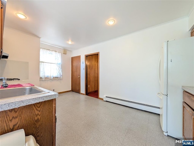 kitchen featuring a sink, light countertops, freestanding refrigerator, a baseboard heating unit, and ornamental molding