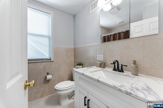 bathroom with visible vents, a wealth of natural light, toilet, and tile walls