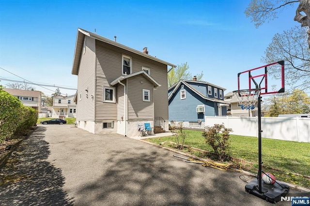 rear view of property with a lawn, fence, and a chimney