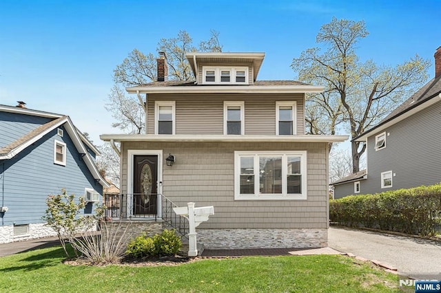 american foursquare style home featuring a chimney and a front yard