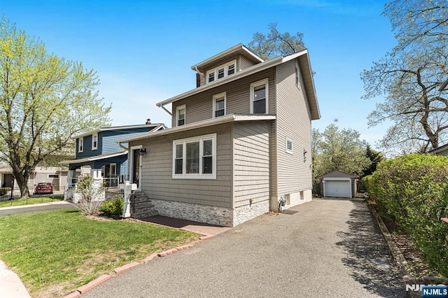 american foursquare style home with an outdoor structure, a garage, a front lawn, and aphalt driveway