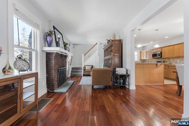 living room featuring stairs, a brick fireplace, hardwood / wood-style floors, baseboards, and recessed lighting