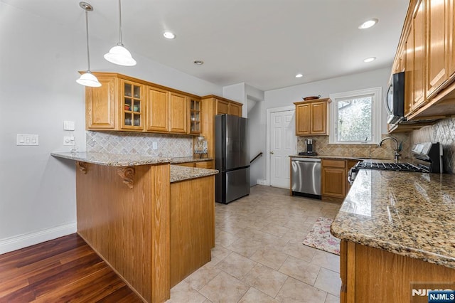 kitchen with a kitchen bar, appliances with stainless steel finishes, tasteful backsplash, a peninsula, and stone counters