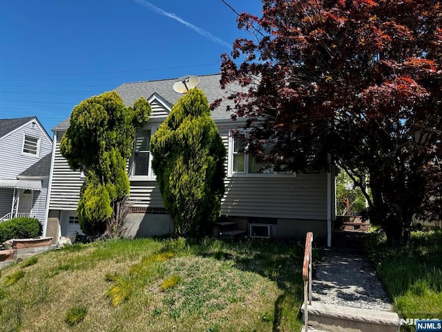 view of front of house featuring a shingled roof and a front yard