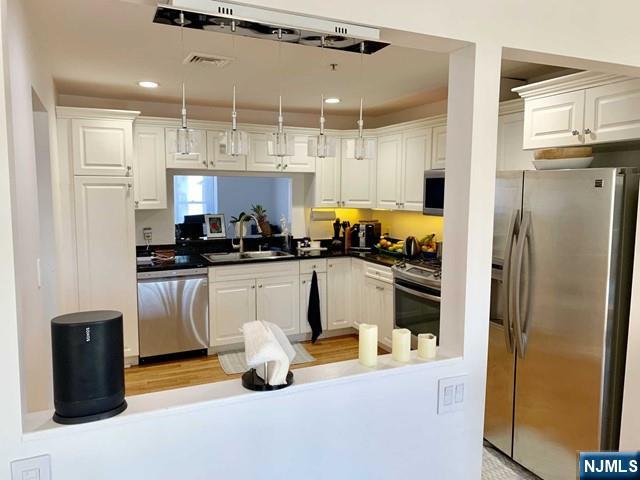 48 Legend Hills Dr, Edgewater, NJ 07020 - kitchen with white cabinets, dark countertops, appliances with stainless steel finishes, and a sink