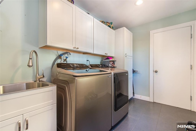 clothes washing area with a sink, dark tile patterned flooring, cabinet space, and washer and dryer