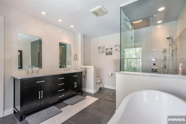 bathroom with a sink, double vanity, tiled shower, and a freestanding bath