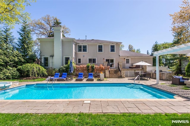 view of swimming pool featuring a pool with connected hot tub, exterior kitchen, an outdoor hangout area, a wooden deck, and a patio area