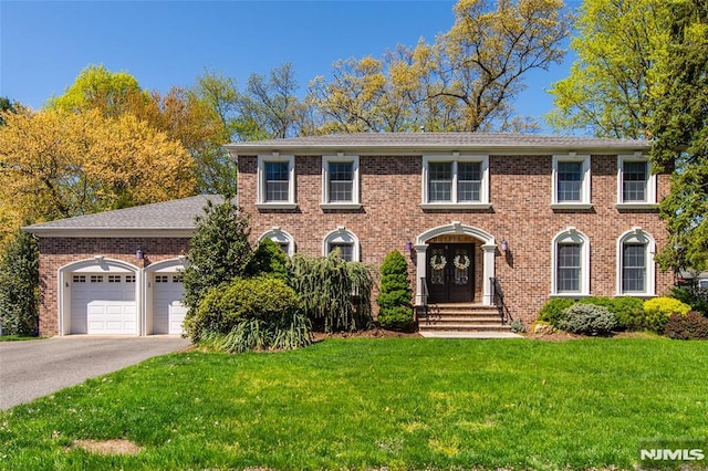colonial house with brick siding, a garage, driveway, and a front yard