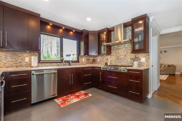 kitchen featuring wall chimney range hood, a sink, stainless steel appliances, tasteful backsplash, and ornamental molding