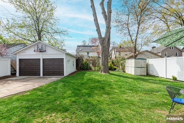 view of yard featuring fence, an outdoor structure, and a garage