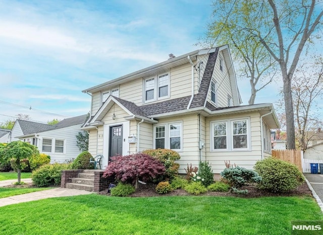view of front of property with a gambrel roof, a front lawn, and roof with shingles