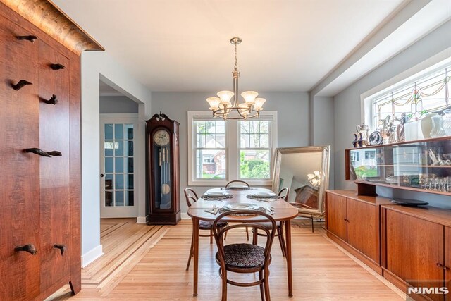 dining space with light wood-style flooring and a notable chandelier