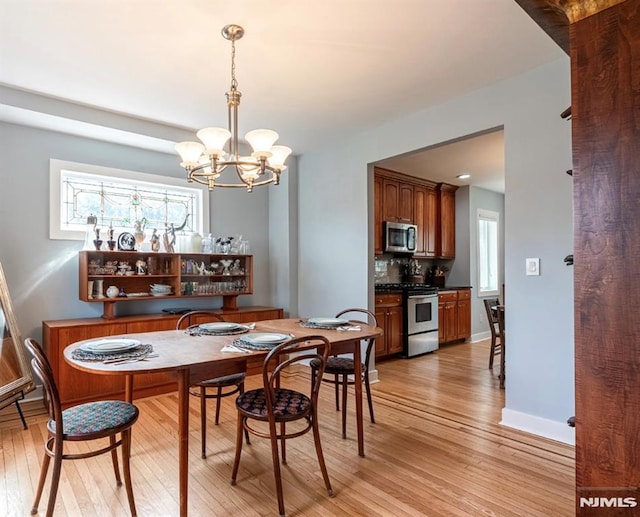 dining area with light wood-style floors and a notable chandelier