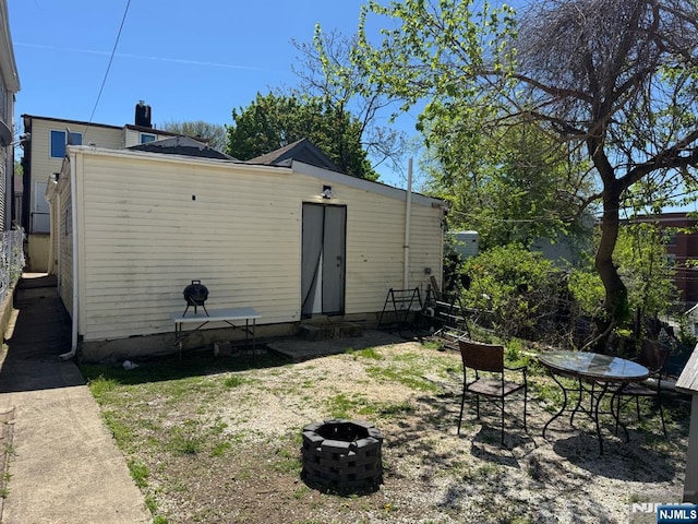 rear view of property with entry steps and a fire pit